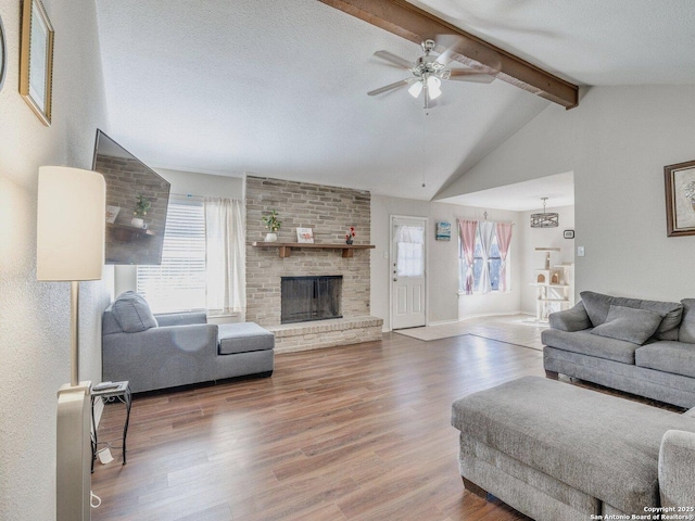 living room with ceiling fan, a fireplace, wood-type flooring, lofted ceiling with beams, and a textured ceiling