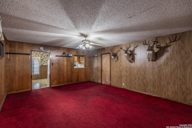 empty room featuring ceiling fan, a textured ceiling, and dark colored carpet