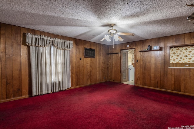 spare room with washer / dryer, carpet floors, a textured ceiling, and wooden walls