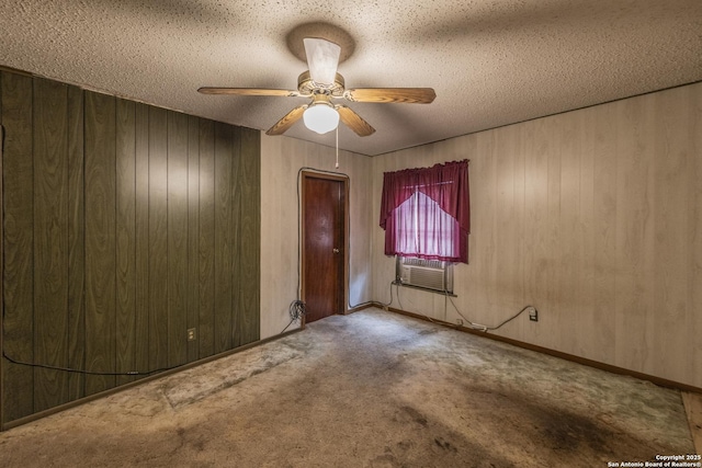 carpeted empty room featuring a textured ceiling, a wall unit AC, ceiling fan, and wood walls