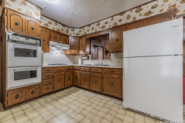 kitchen with white appliances, sink, and a textured ceiling