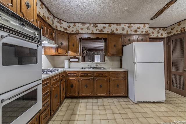 kitchen featuring white appliances, sink, and a textured ceiling