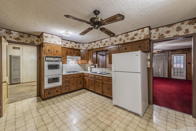 kitchen featuring sink, white appliances, a textured ceiling, and ceiling fan