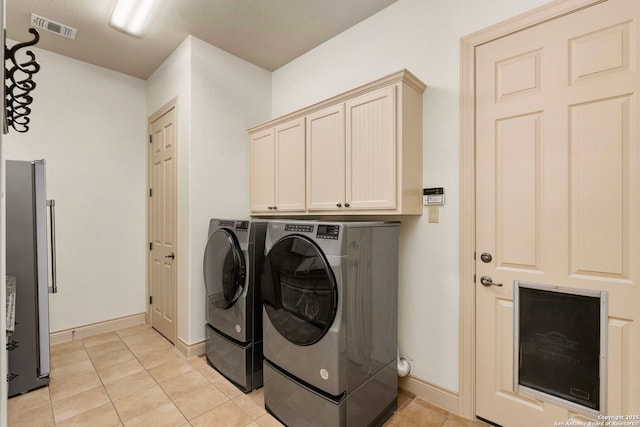 laundry room with cabinets, light tile patterned flooring, and separate washer and dryer