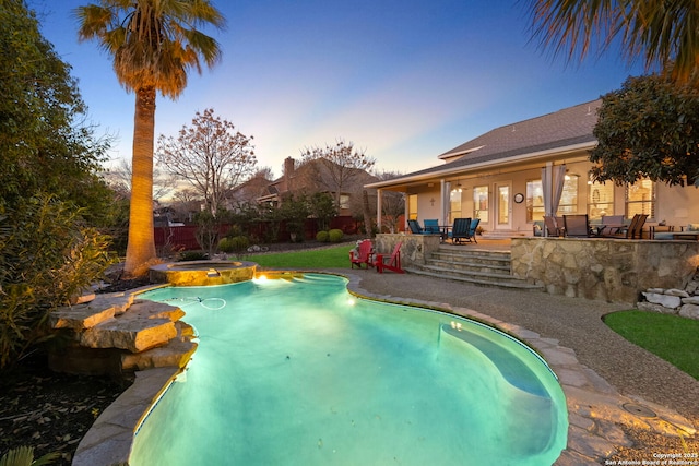 pool at dusk with an in ground hot tub and a patio area