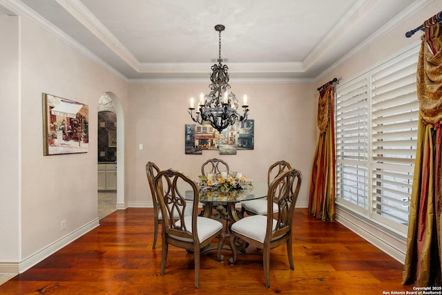 dining room featuring ornamental molding, dark hardwood / wood-style floors, a tray ceiling, and a notable chandelier