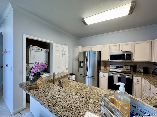 kitchen with crown molding, appliances with stainless steel finishes, stone countertops, and stacked washer and clothes dryer