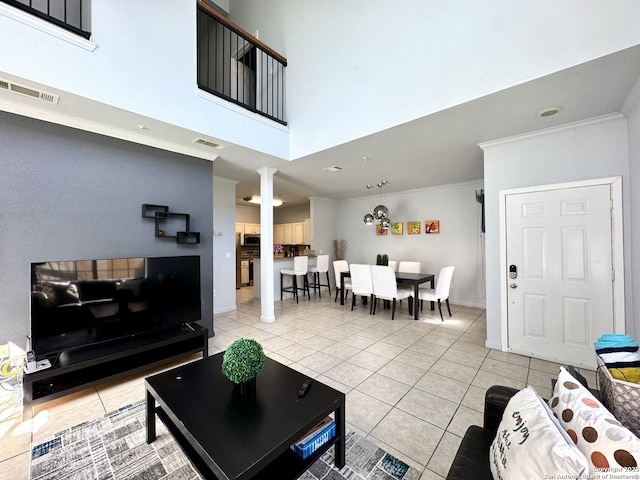 tiled living room with decorative columns, crown molding, and a towering ceiling