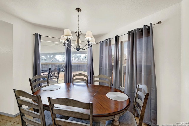 tiled dining area with a chandelier and a textured ceiling