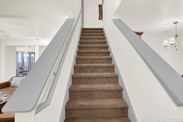 stairway featuring a notable chandelier