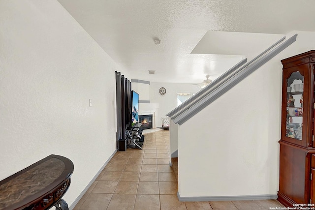 interior space with ceiling fan, tile patterned flooring, and a textured ceiling