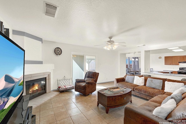 tiled living room with ceiling fan with notable chandelier and a textured ceiling