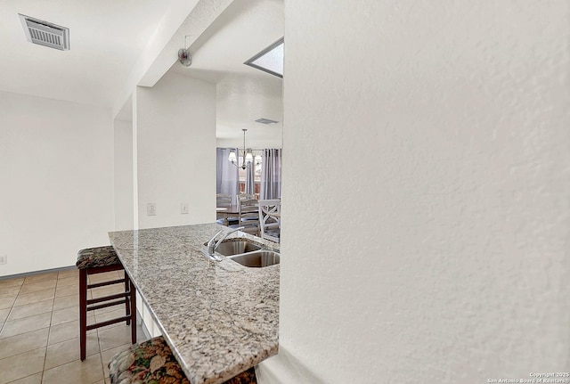 kitchen with pendant lighting, a breakfast bar area, a chandelier, light tile patterned floors, and kitchen peninsula