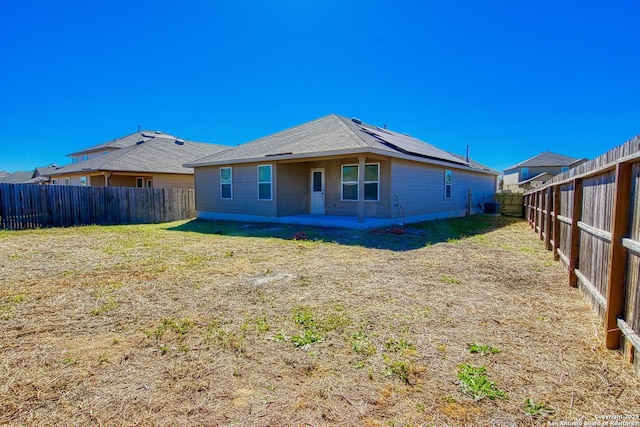 back of house featuring cooling unit, a yard, and solar panels