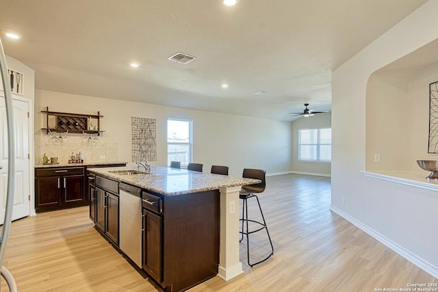 kitchen featuring sink, dishwasher, a kitchen breakfast bar, light hardwood / wood-style floors, and a center island with sink