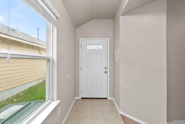 doorway with light tile patterned floors, vaulted ceiling, and a wealth of natural light