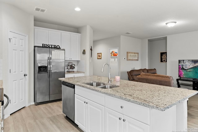 kitchen with appliances with stainless steel finishes, white cabinetry, sink, a kitchen island with sink, and light hardwood / wood-style flooring