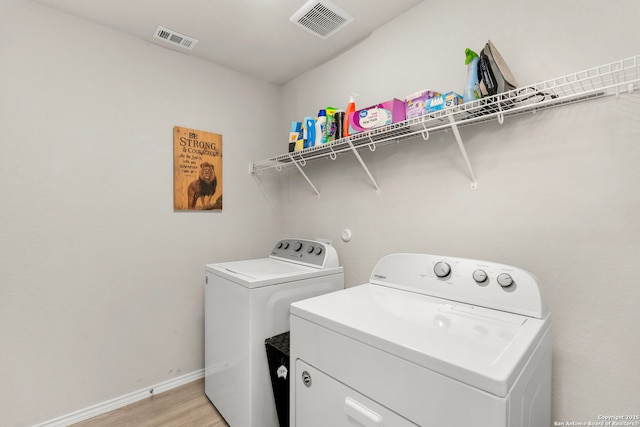 laundry room featuring washing machine and dryer and light wood-type flooring