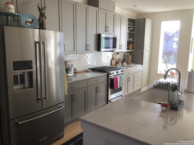 kitchen featuring gray cabinets, light stone countertops, appliances with stainless steel finishes, and sink