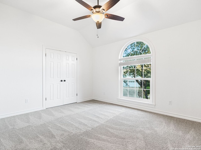 carpeted empty room with lofted ceiling and ceiling fan