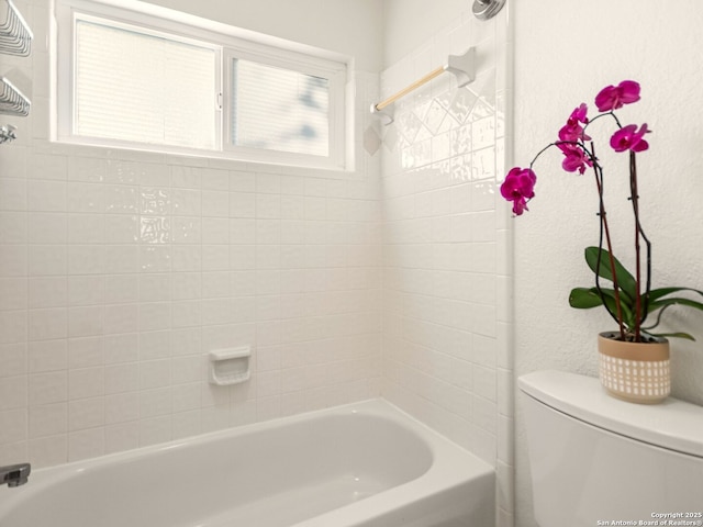 bathroom with tiled shower / bath combo and toilet