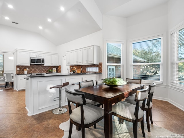 dining area featuring high vaulted ceiling and light tile patterned flooring