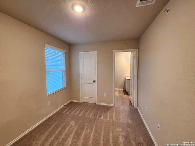 unfurnished bedroom with light colored carpet and a textured ceiling