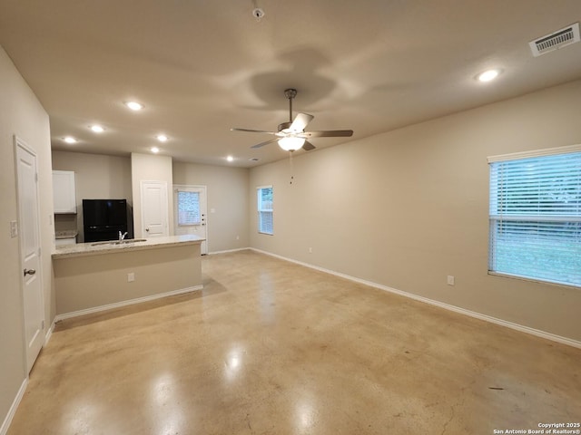 unfurnished living room featuring ceiling fan and sink