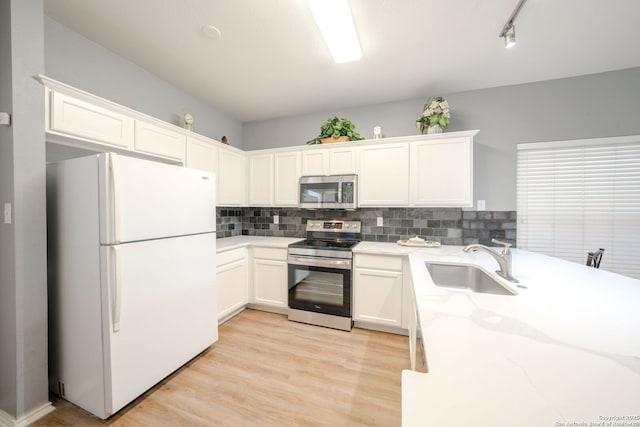 kitchen with sink, appliances with stainless steel finishes, light stone counters, white cabinets, and decorative backsplash