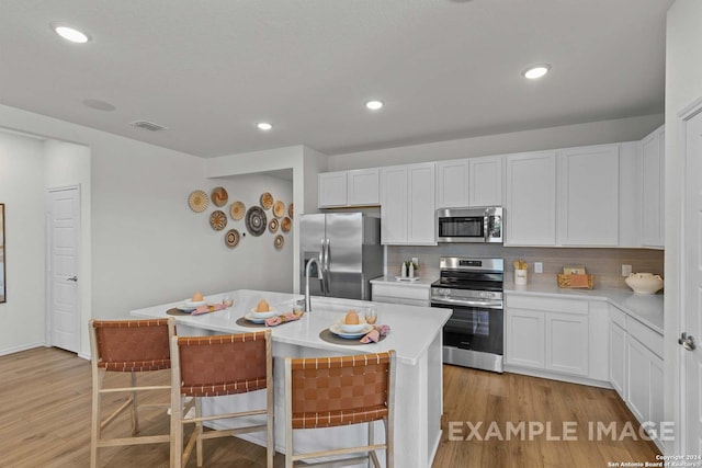 kitchen featuring stainless steel appliances, white cabinetry, an island with sink, and a kitchen breakfast bar