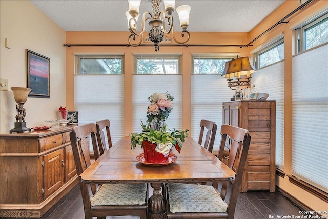 dining space featuring a notable chandelier, dark wood-type flooring, and a textured ceiling