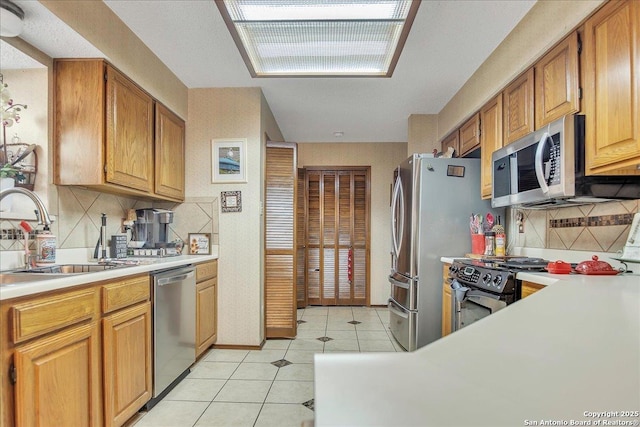 kitchen with light tile patterned flooring, stainless steel appliances, sink, and decorative backsplash