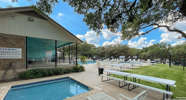 view of swimming pool featuring ceiling fan, a patio, and a lawn