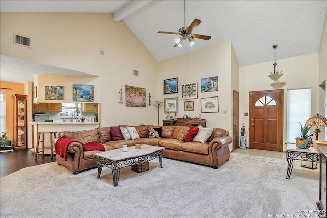 living room with beamed ceiling, high vaulted ceiling, light colored carpet, and ceiling fan