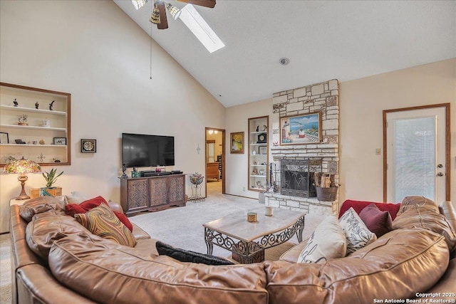 living room with a stone fireplace, high vaulted ceiling, a skylight, carpet floors, and ceiling fan