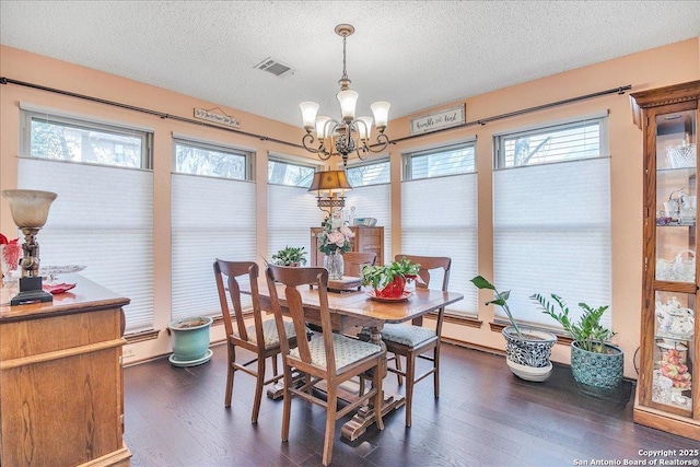 dining area featuring dark hardwood / wood-style flooring, a textured ceiling, a wealth of natural light, and a chandelier