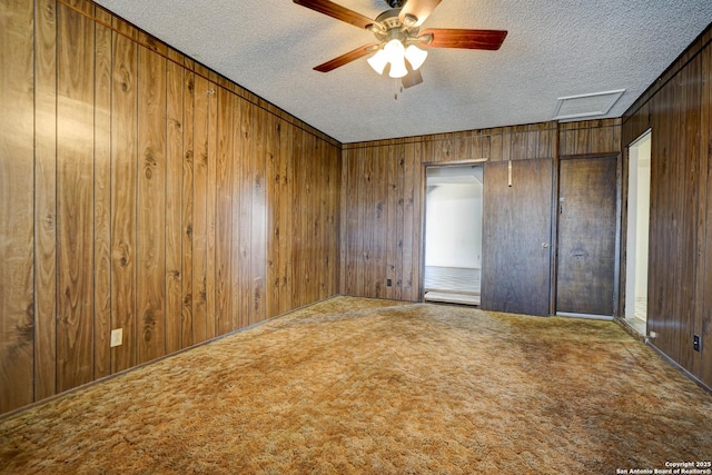 empty room featuring carpet floors, a textured ceiling, and wooden walls