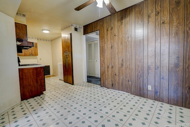 kitchen featuring ceiling fan and wooden walls