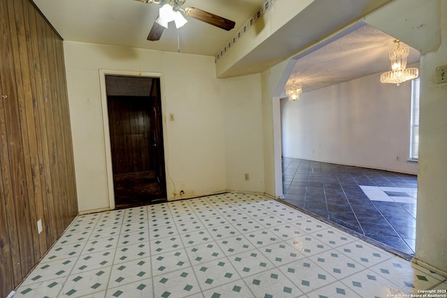 spare room with ceiling fan with notable chandelier