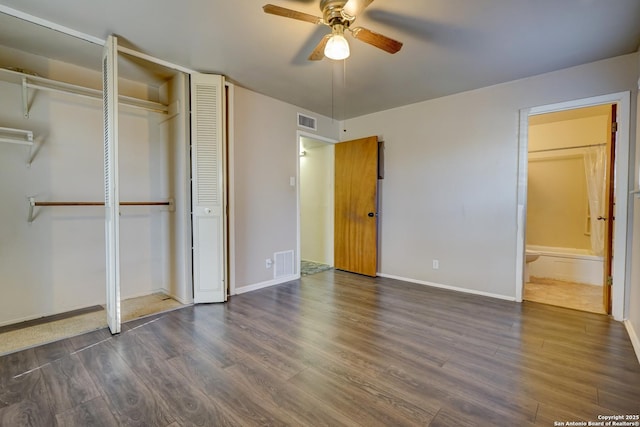 unfurnished bedroom featuring ensuite bathroom, ceiling fan, dark hardwood / wood-style flooring, and a closet