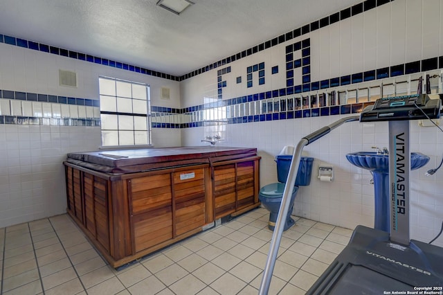 interior space with a textured ceiling, tile walls, and light tile patterned floors