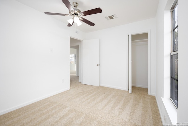 unfurnished bedroom featuring ceiling fan, a closet, and light carpet