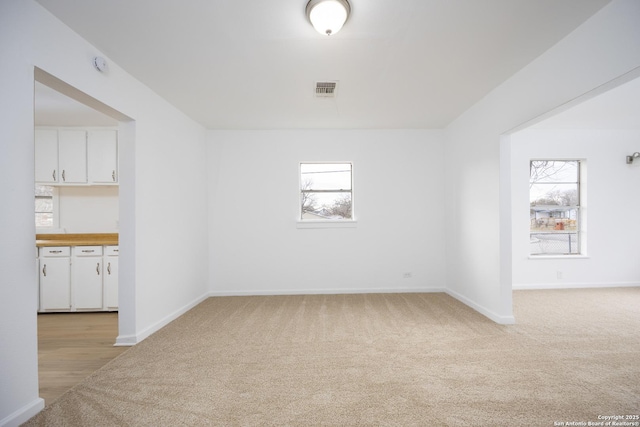 unfurnished room featuring light carpet and a wealth of natural light