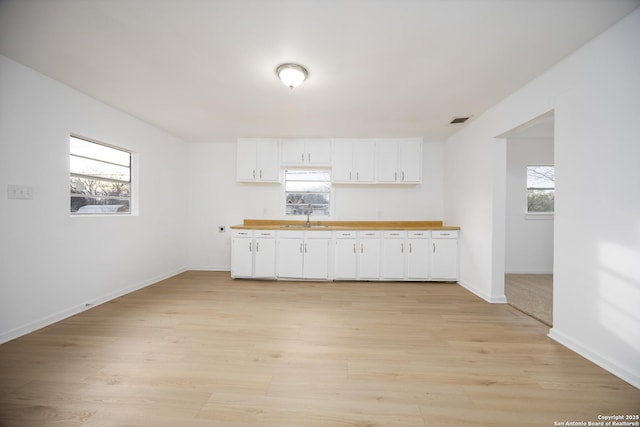 kitchen with white cabinetry, plenty of natural light, light hardwood / wood-style floors, and sink