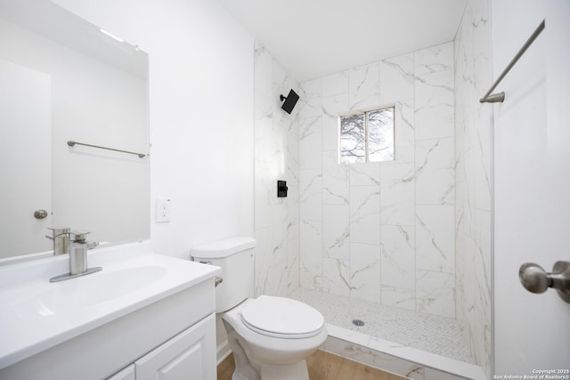 bathroom featuring tiled shower, vanity, and toilet