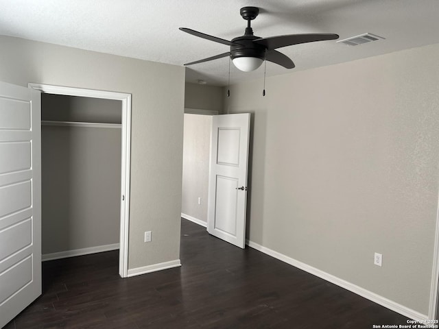 unfurnished bedroom featuring dark wood-type flooring, ceiling fan, a closet, and a textured ceiling