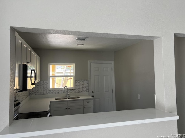 kitchen with sink, decorative backsplash, a textured ceiling, and range