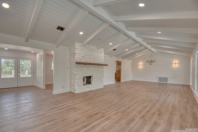 unfurnished living room with hardwood / wood-style flooring, a stone fireplace, vaulted ceiling with beams, and french doors