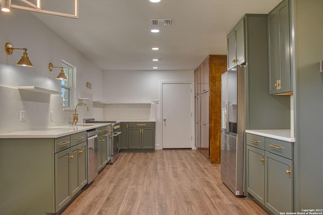 kitchen featuring tasteful backsplash, dishwasher, sink, green cabinets, and light wood-type flooring