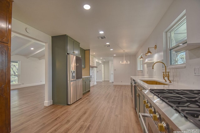 kitchen featuring sink, decorative light fixtures, light wood-type flooring, green cabinets, and stainless steel appliances